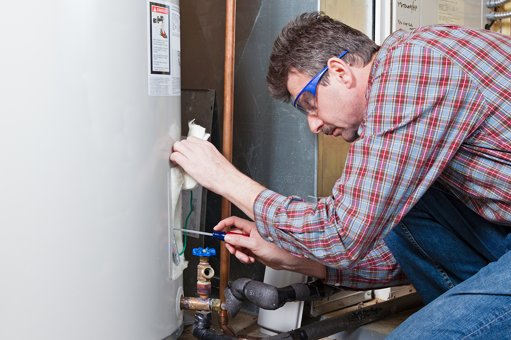 A plumber is performing maintenance on a residential water heater